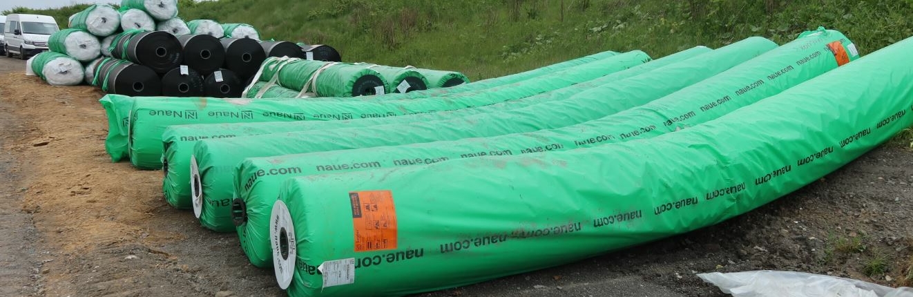 oberflaecehnabdichtung Grüne Rohre liegen auf einer Grünfläche