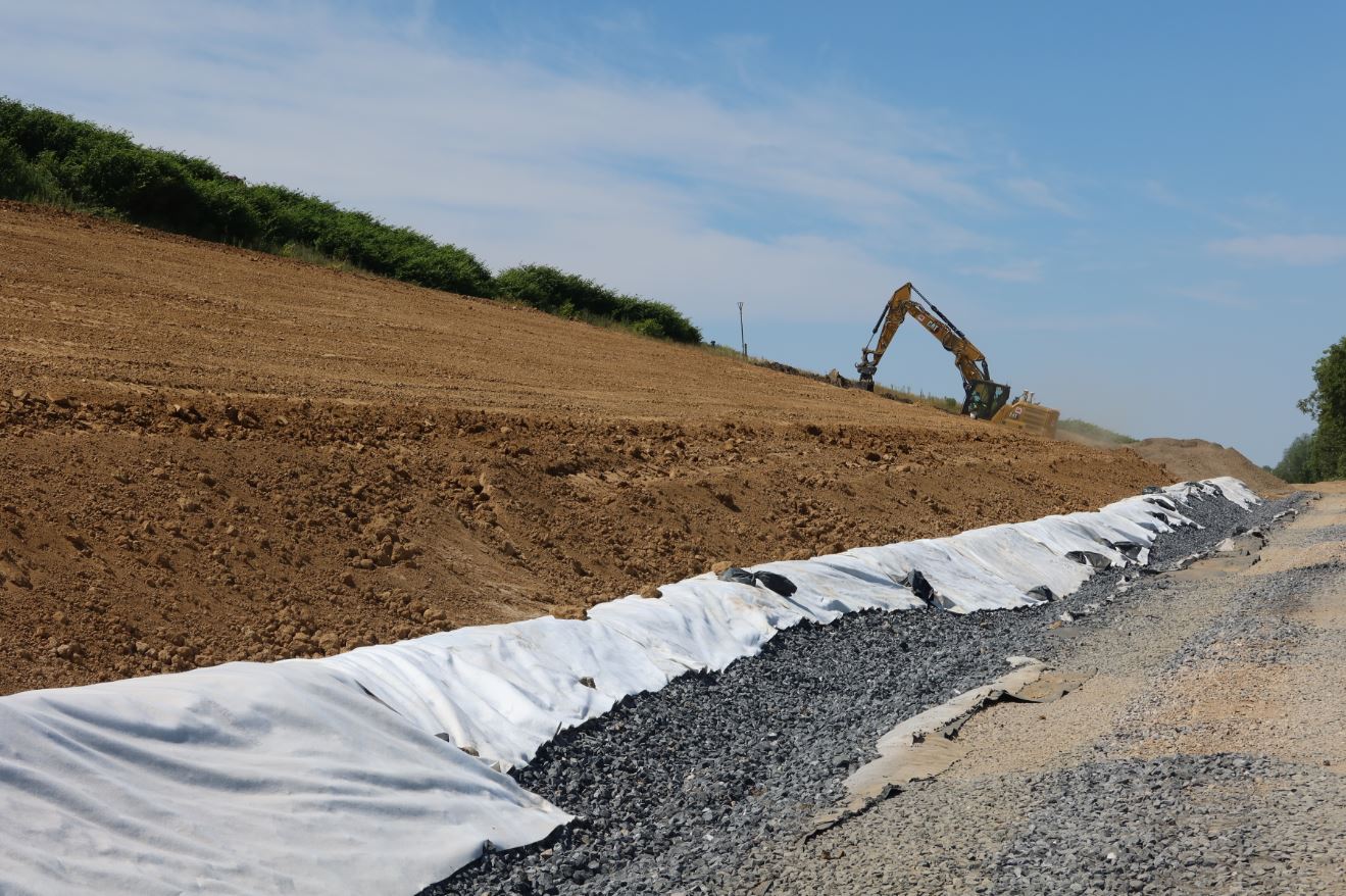 oberflaecehnabdichtung Ein Bagger fährt einen Sandhügel hinauf
