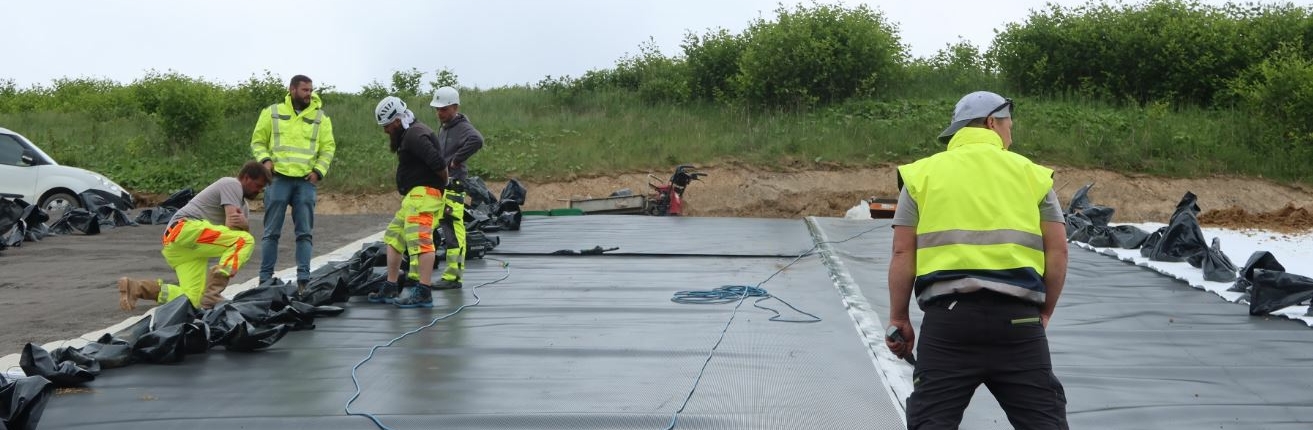 oberflaecehnabdichtung Arbeiter stehen in gelben Anziehsachen auf einer Baufläche