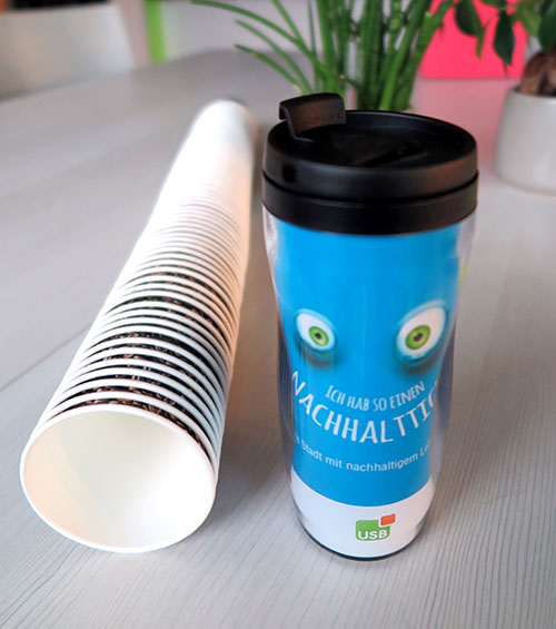 Becher Blauer Becher mit Augen steht neben liegenden Kaffeebecher