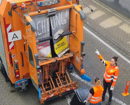 Matchday Zwei Frauen in orangenen Westen laden Müll in einen Müllwagen