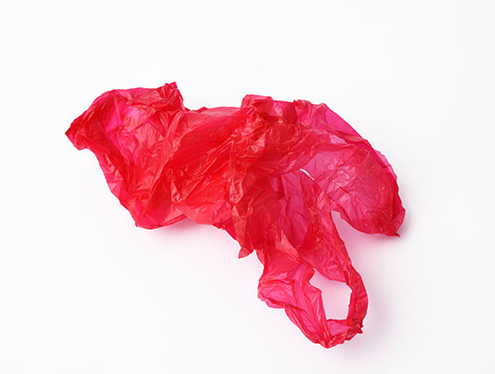 Crumpled red plastic shopping bag on white background Rote Plastiktüte liegt auf dem Boden